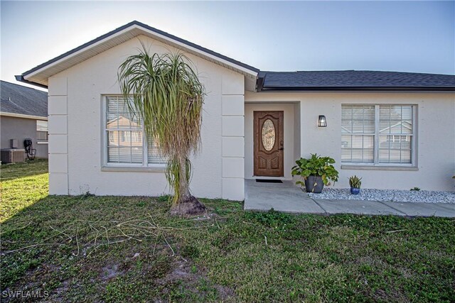 ranch-style home with a front yard and central air condition unit