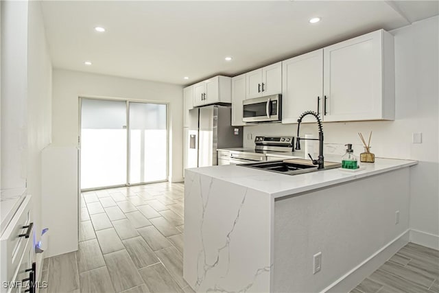 kitchen featuring white cabinetry, sink, stainless steel appliances, and kitchen peninsula