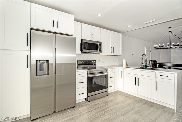 kitchen with appliances with stainless steel finishes, sink, white cabinets, and an inviting chandelier