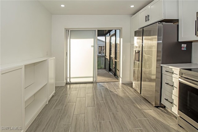 kitchen featuring stove, stainless steel fridge with ice dispenser, and white cabinets