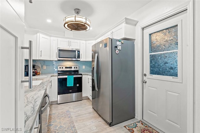 kitchen with light stone countertops, stainless steel appliances, tasteful backsplash, light hardwood / wood-style flooring, and white cabinets