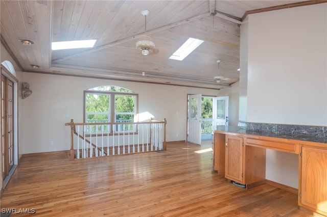 empty room featuring a skylight, a wealth of natural light, light hardwood / wood-style flooring, and wooden ceiling