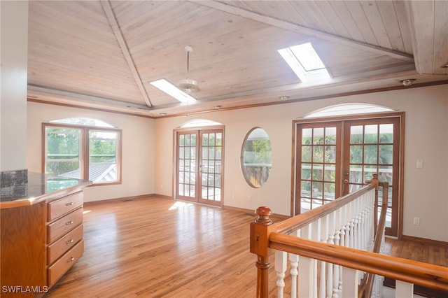 interior space featuring french doors, light wood-type flooring, lofted ceiling with skylight, and wooden ceiling