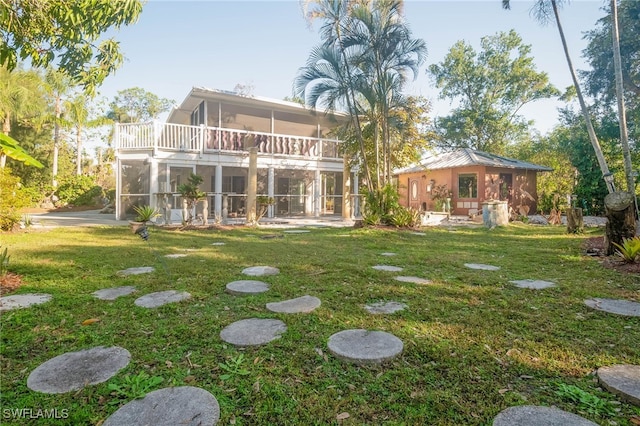 rear view of house with a lawn and a balcony