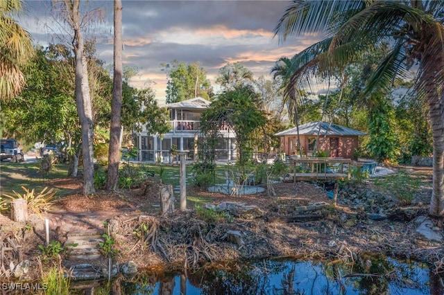 back house at dusk featuring a water view and a balcony