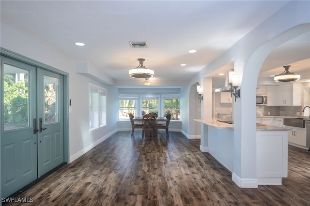 kitchen with white cabinetry, sink, light stone countertops, dark hardwood / wood-style floors, and backsplash