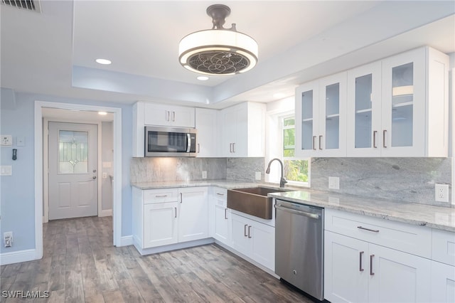 kitchen featuring white cabinetry, sink, stainless steel appliances, backsplash, and a tray ceiling