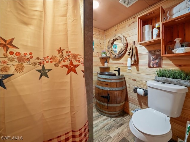 bathroom with wood-type flooring, vanity, toilet, and wooden walls