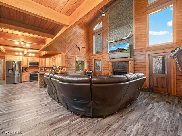 living room featuring beam ceiling, hardwood / wood-style floors, a towering ceiling, and wood ceiling