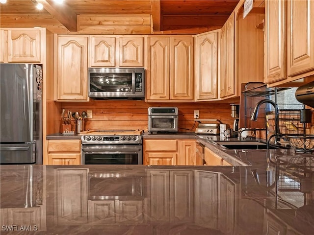 kitchen with beamed ceiling, appliances with stainless steel finishes, sink, and wood walls