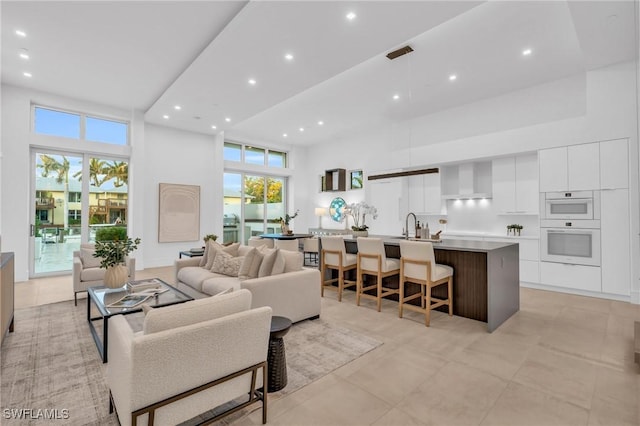 living room featuring a towering ceiling and sink