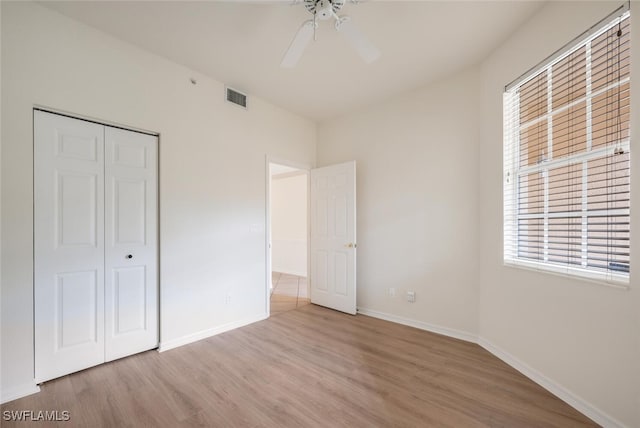 unfurnished bedroom with ceiling fan, light wood-type flooring, and a closet