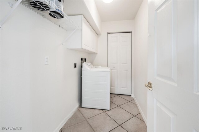 clothes washing area with washer / clothes dryer, light tile patterned flooring, and cabinets