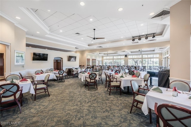 dining space featuring dark colored carpet, ceiling fan, a raised ceiling, and ornamental molding