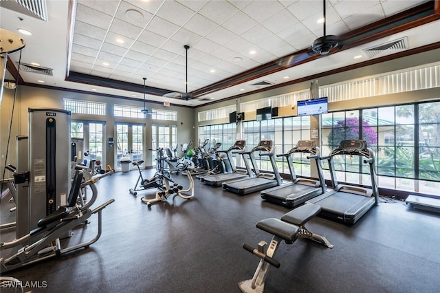 workout area with a high ceiling, a raised ceiling, ceiling fan, and crown molding