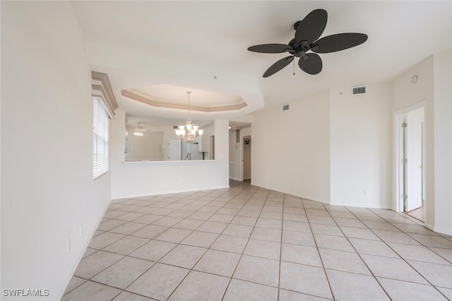 tiled spare room with ceiling fan with notable chandelier and a raised ceiling