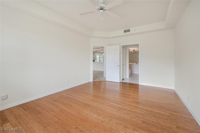 unfurnished room featuring light wood-type flooring, a raised ceiling, and ceiling fan