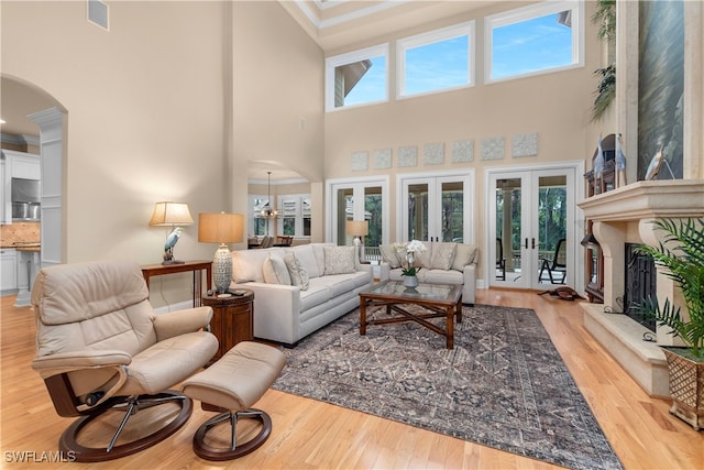 living room with crown molding, french doors, a high ceiling, and light wood-type flooring