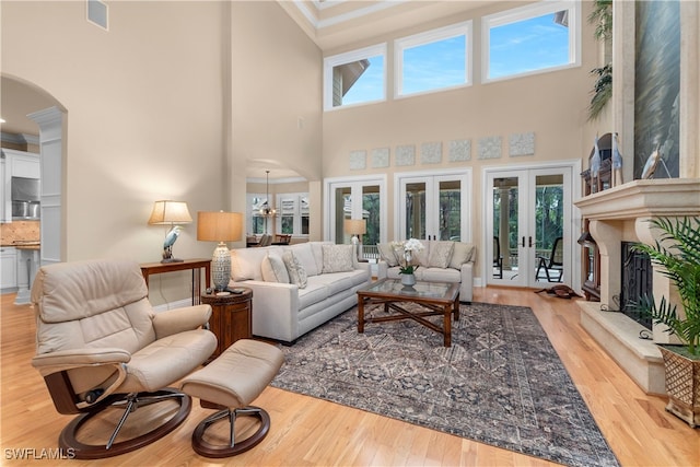 12261 Hammock Creek Way, Fort Myers, FL 33905 - living area with arched walkways, french doors, a towering ceiling, wood finished floors, and a fireplace with raised hearth