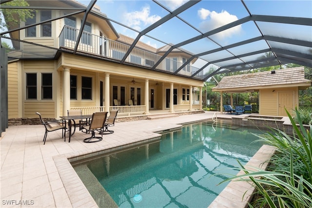 view of swimming pool featuring glass enclosure, ceiling fan, a patio area, and an in ground hot tub