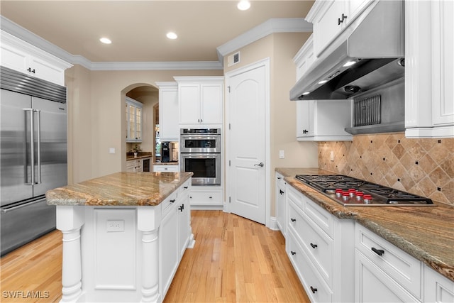 kitchen featuring decorative backsplash, appliances with stainless steel finishes, light stone counters, crown molding, and white cabinets