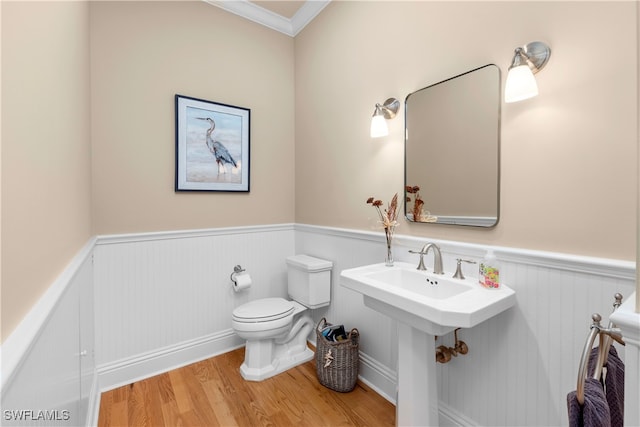 bathroom featuring wood-type flooring, toilet, and crown molding