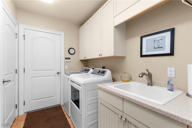 washroom with hardwood / wood-style floors, washer and dryer, cabinets, and sink