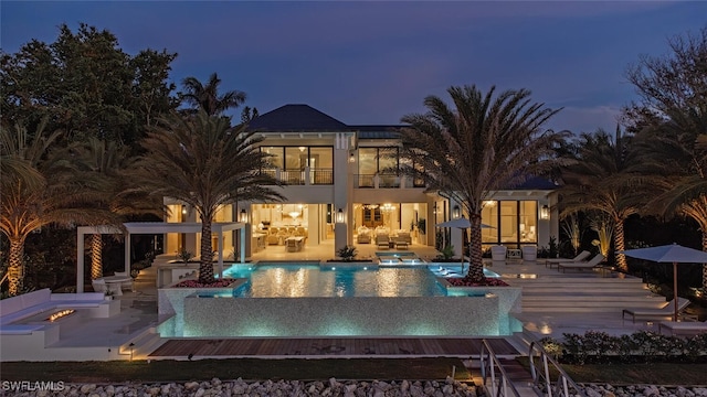 pool at dusk featuring a patio area, an outdoor living space with a fire pit, and a hot tub