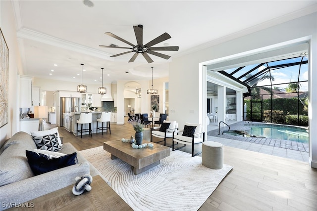 living room featuring light wood-type flooring, ceiling fan, and ornamental molding