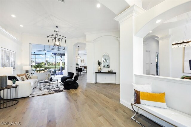 living room featuring light hardwood / wood-style floors, an inviting chandelier, and ornamental molding