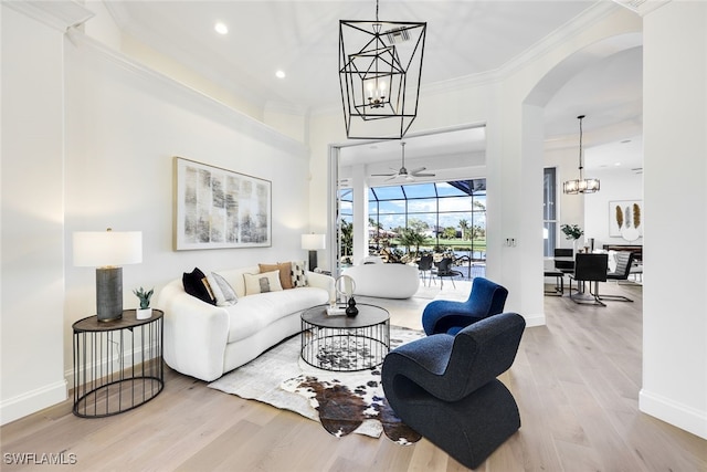 living room featuring crown molding, ceiling fan with notable chandelier, and light wood-type flooring