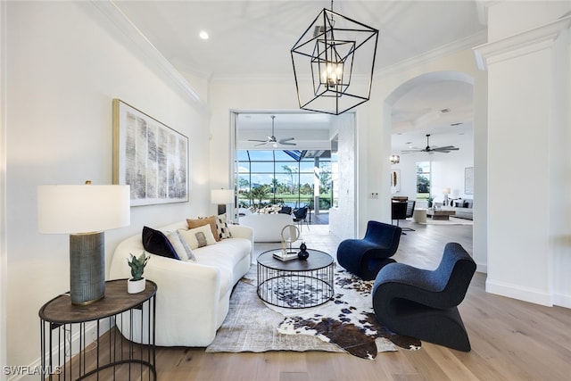 living room with ceiling fan with notable chandelier, light hardwood / wood-style floors, and ornamental molding