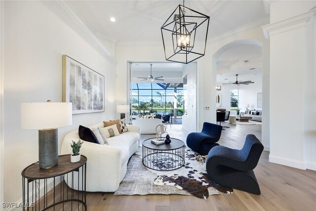 living room with ornamental molding, a wealth of natural light, a sunroom, and light wood-style flooring