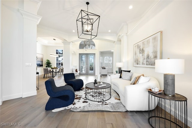 living room with french doors, wood finished floors, decorative columns, and crown molding