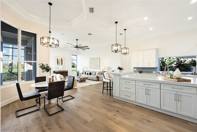 kitchen with open floor plan, ornamental molding, white cabinetry, and decorative light fixtures