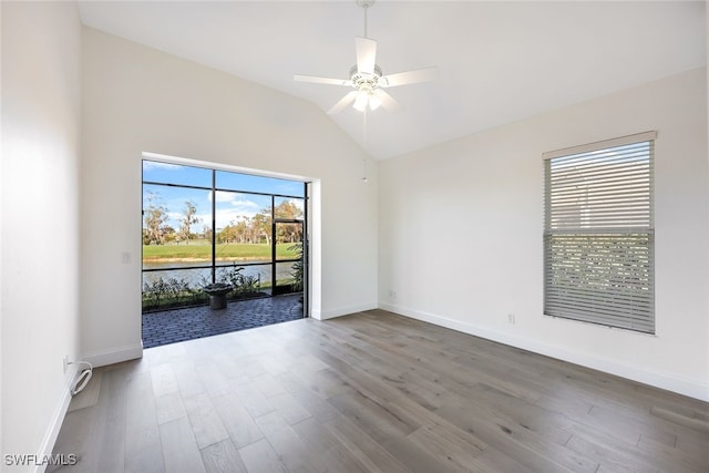 spare room with ceiling fan, a water view, wood-type flooring, and lofted ceiling