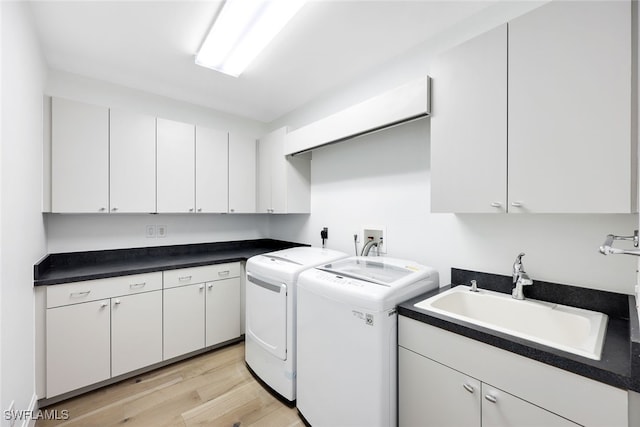 laundry area with washer and clothes dryer, sink, cabinets, and light wood-type flooring