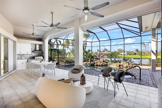 view of patio featuring glass enclosure, area for grilling, and a water view