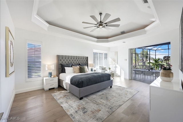 bedroom featuring a raised ceiling, access to exterior, ceiling fan, and wood-type flooring