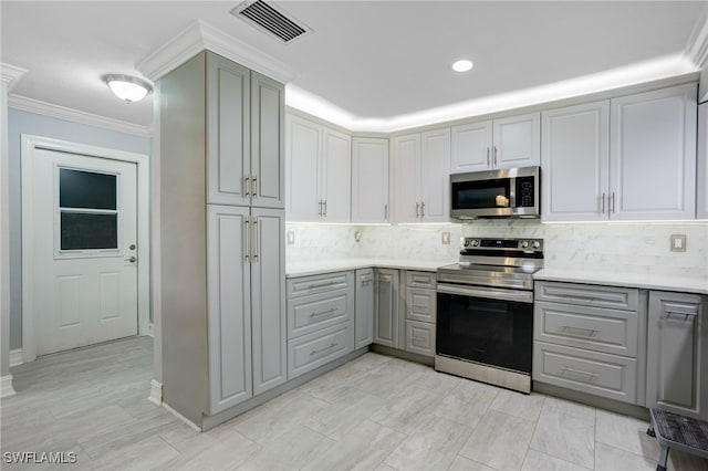 kitchen featuring decorative backsplash, appliances with stainless steel finishes, ornamental molding, and gray cabinetry