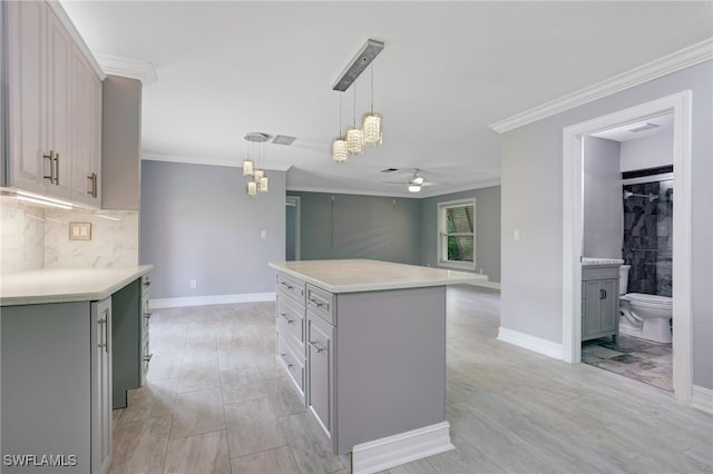 kitchen featuring pendant lighting, gray cabinetry, a center island, crown molding, and ceiling fan