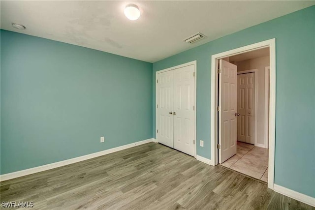 unfurnished bedroom with light hardwood / wood-style floors and a closet