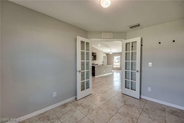 tiled empty room with lofted ceiling and french doors