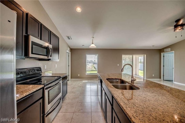 kitchen featuring sink, light tile patterned floors, dark brown cabinets, light stone counters, and stainless steel appliances