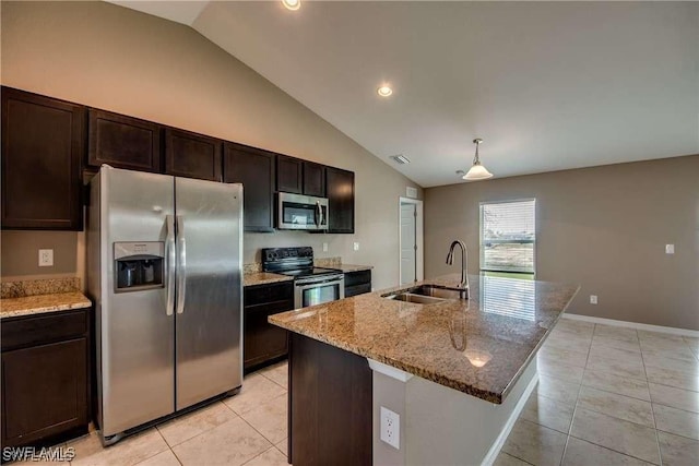 kitchen featuring a kitchen island with sink, sink, light stone countertops, dark brown cabinetry, and stainless steel appliances