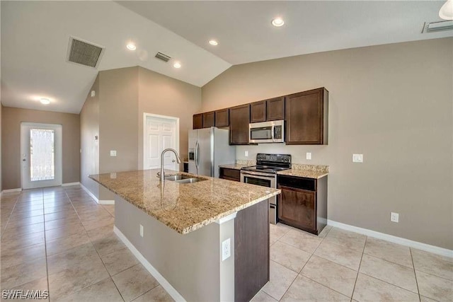 kitchen featuring lofted ceiling, a center island with sink, sink, light tile patterned floors, and appliances with stainless steel finishes