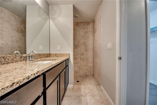 bathroom featuring tile patterned flooring, vanity, and a tile shower