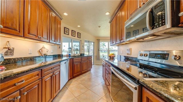 kitchen featuring light tile patterned flooring, appliances with stainless steel finishes, sink, and dark stone counters