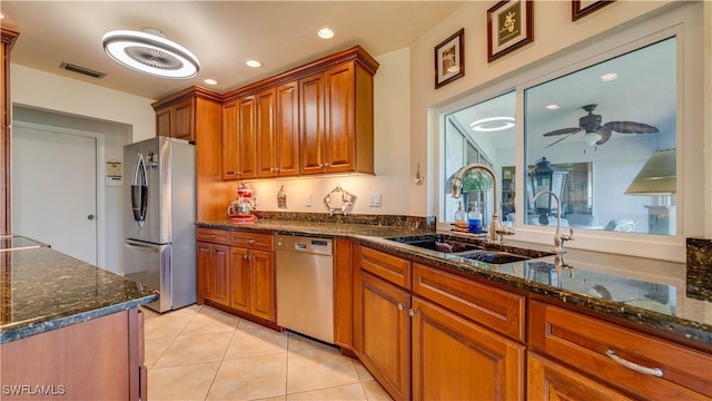 kitchen with light tile patterned flooring, sink, dark stone counters, ceiling fan, and stainless steel appliances