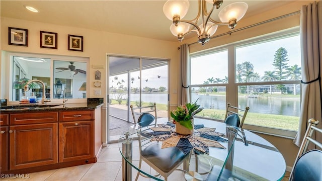 dining area featuring a water view, a notable chandelier, sink, and light tile patterned floors